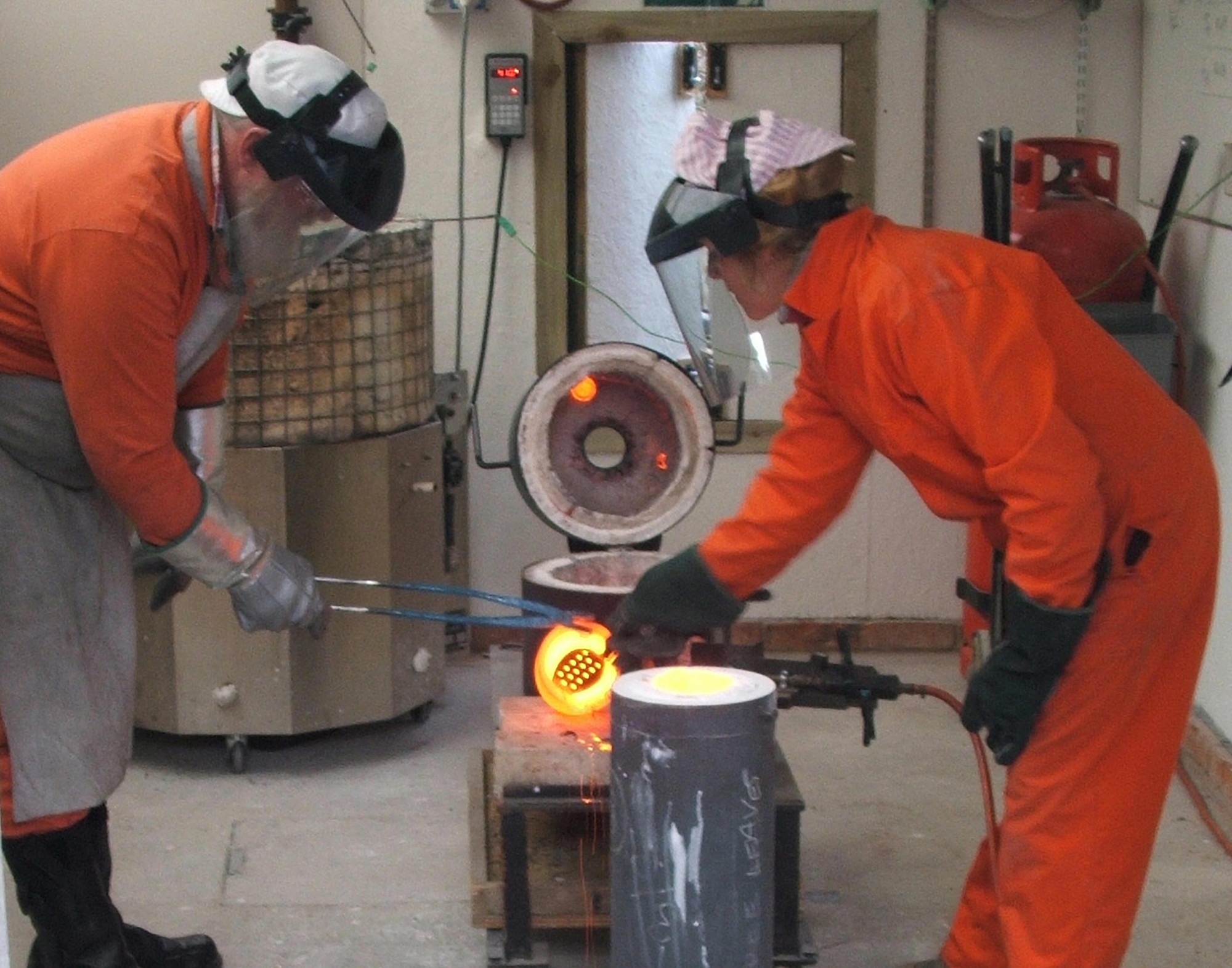 Sioban & Pete casting bronze Sioban & Pete casting bronze - wearing fire-resistant clothing, gloves and visors, pouring molten bronze into a casting flask to make a bronze sculpture